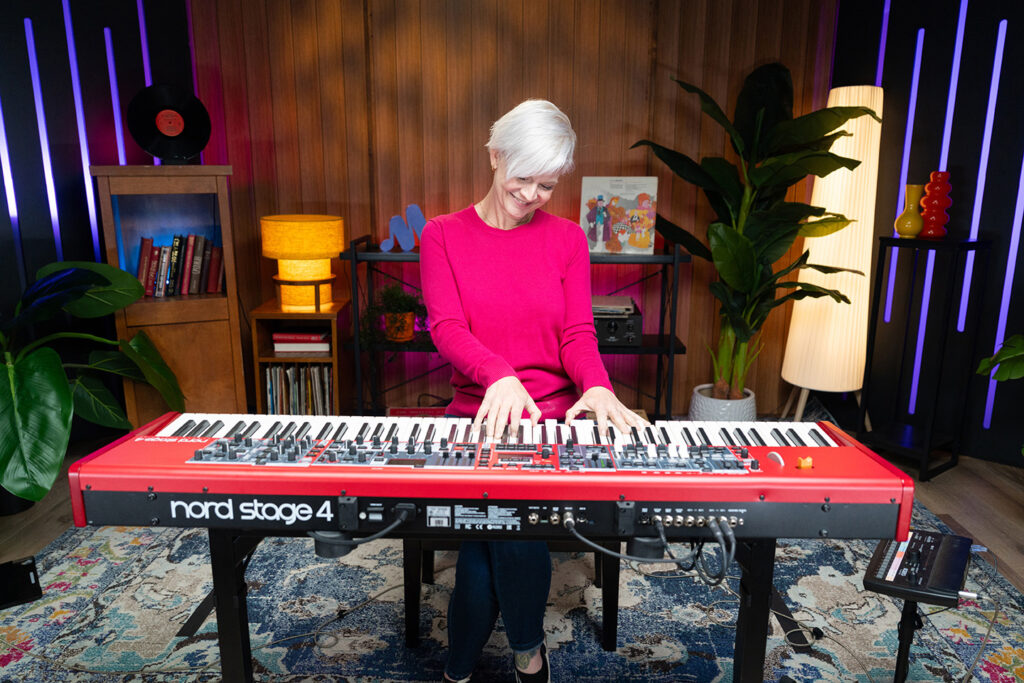 Lisa Witt playing a red Nord Stage 4 keyboard in a music studio