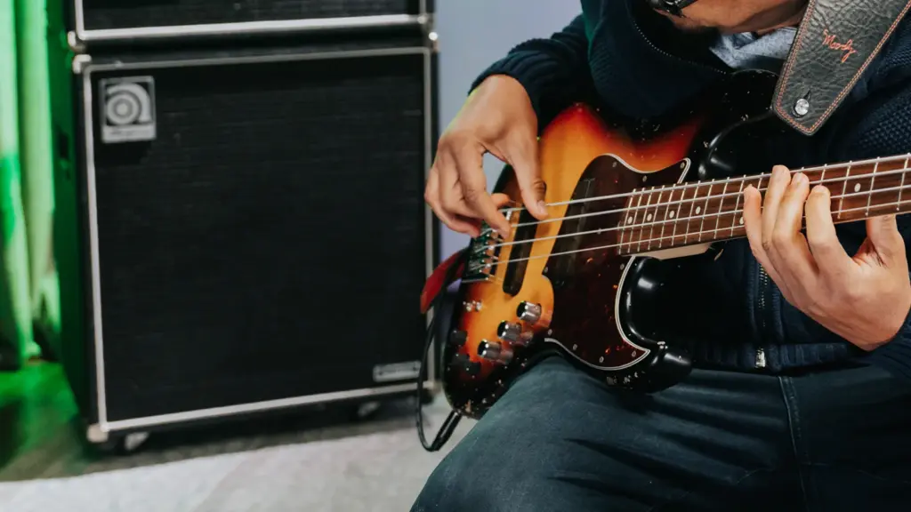 Bass guitarist playing an electric bass beside an amplifier
